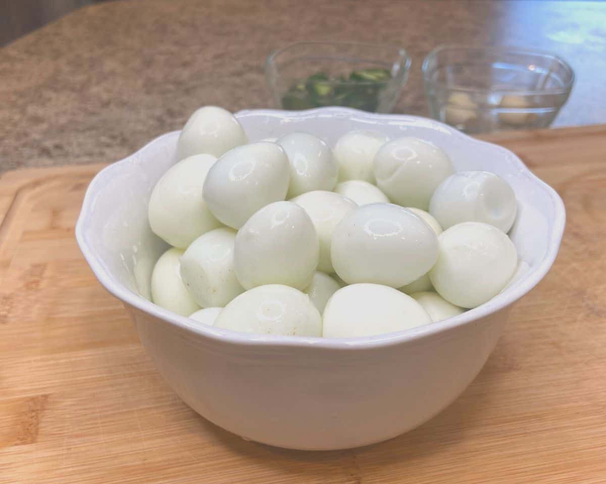 bowl of peeled quail eggs on wood cutting board