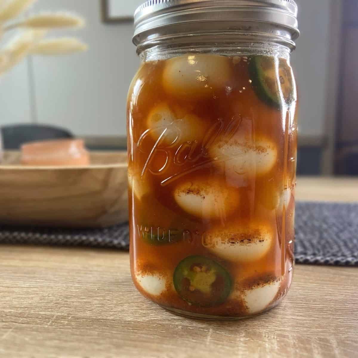 mason jar of quail eggs in a spicy cajun brine