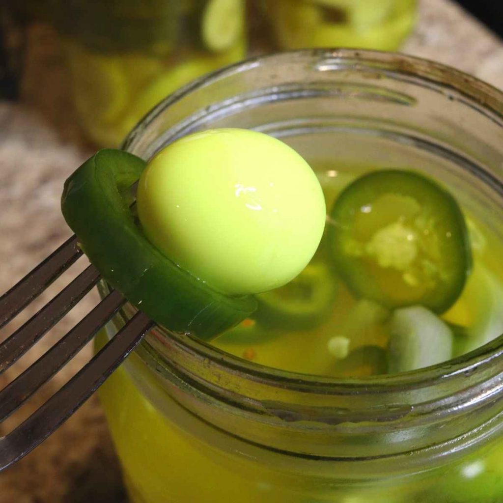 small yellow quail egg on fork with jalapeno