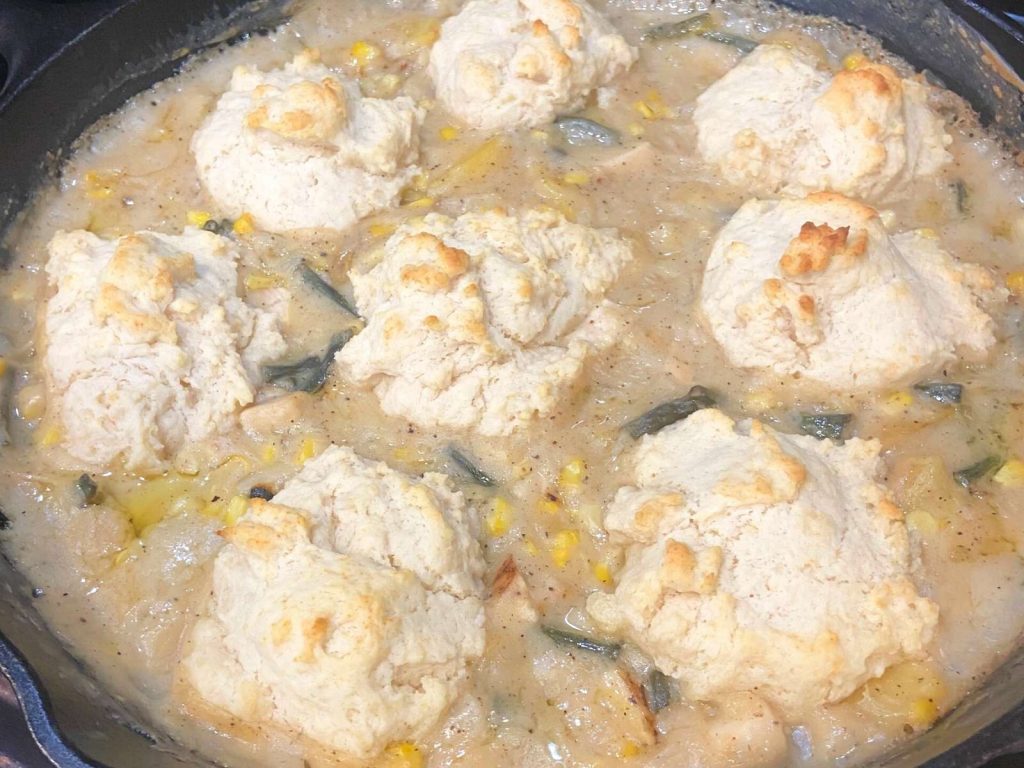 creamy pot pie filling with biscuits on top of it in a cast iron skillet