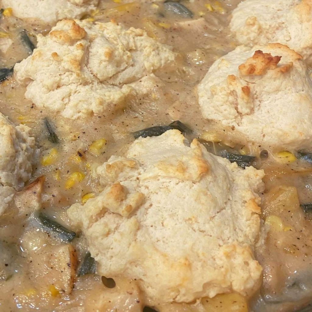 close up creamy pot pie filling with biscuits on top of it in a cast iron skillet