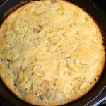 cast iron skillet with cooked cornbread with pieces of yellow squash in it