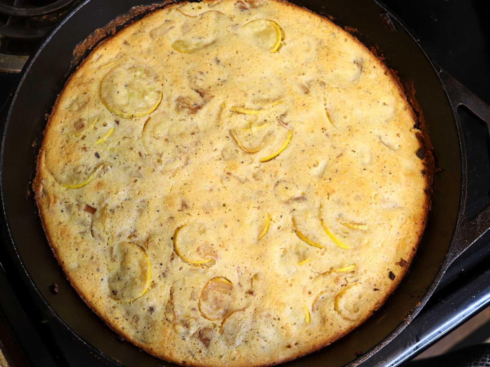 cast iron skillet with cooked cornbread with pieces of yellow squash in it