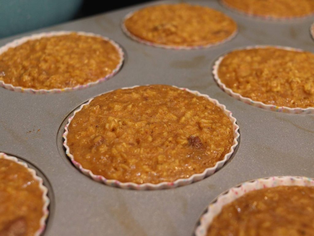 upclose shot of pumpkie pie oatmeal muffins in silicone baking cups in a muffin tin