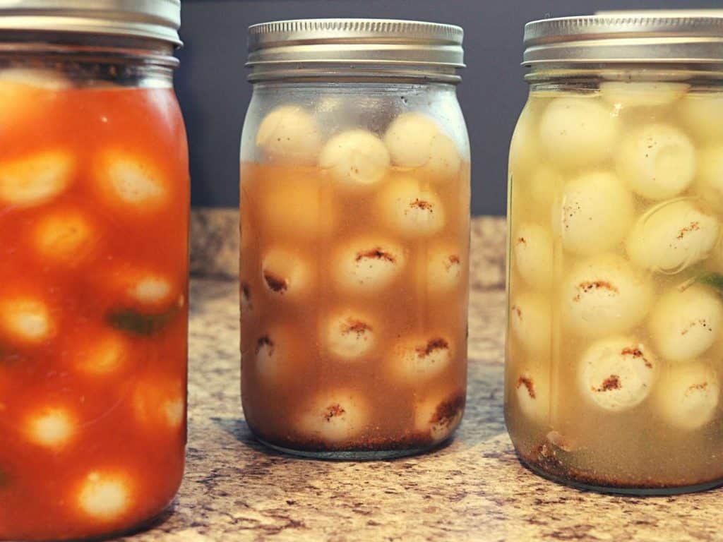 3 mason jars with pickled quail eggs sitting on the counter