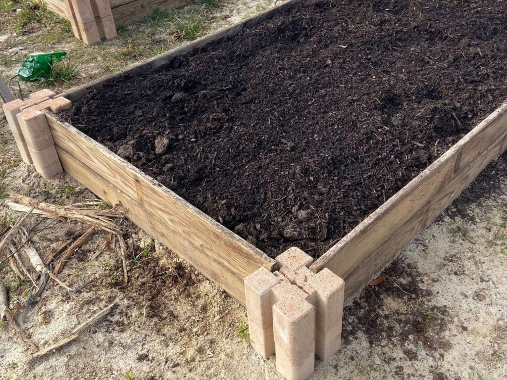 Raised garden bed made from Oldcastle planter walls and 1X6 boards filled with garden soil