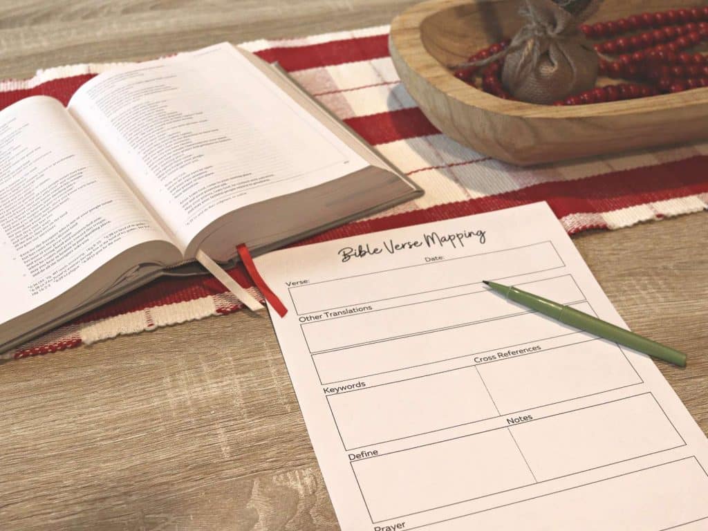open bible and bible study worksheet sitting on table with a pen 
