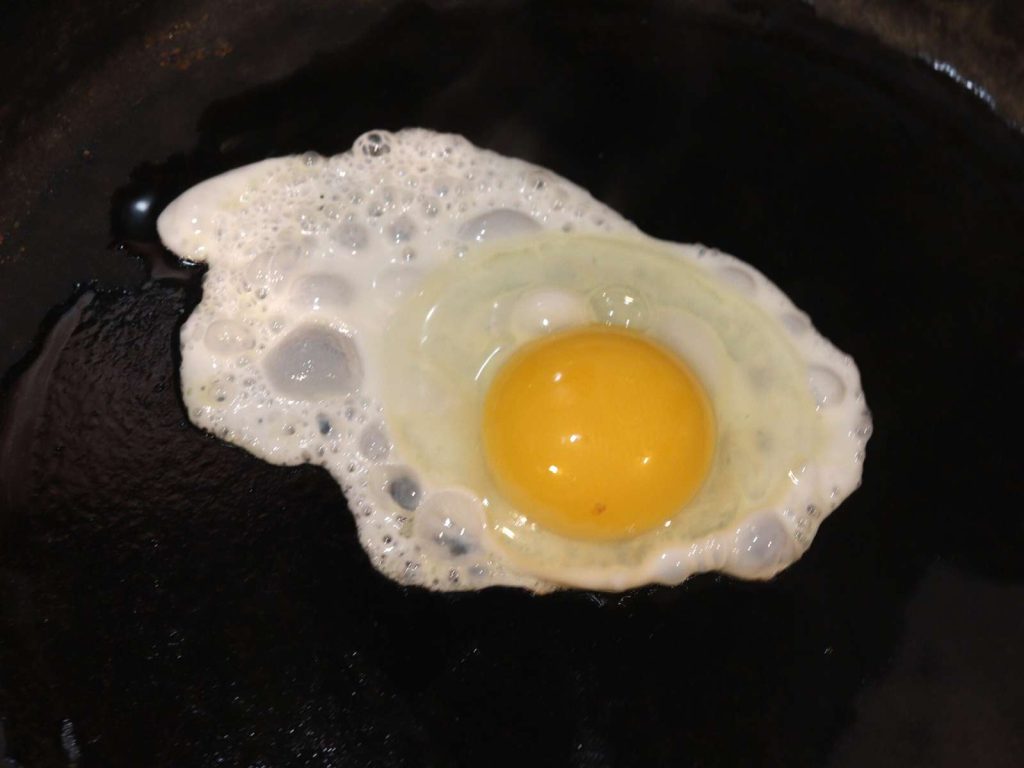 egg frying in cast iron skillet