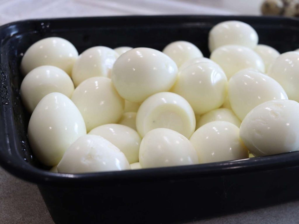 black container full of boiled, peeled quail eggs that had previously been water glassed