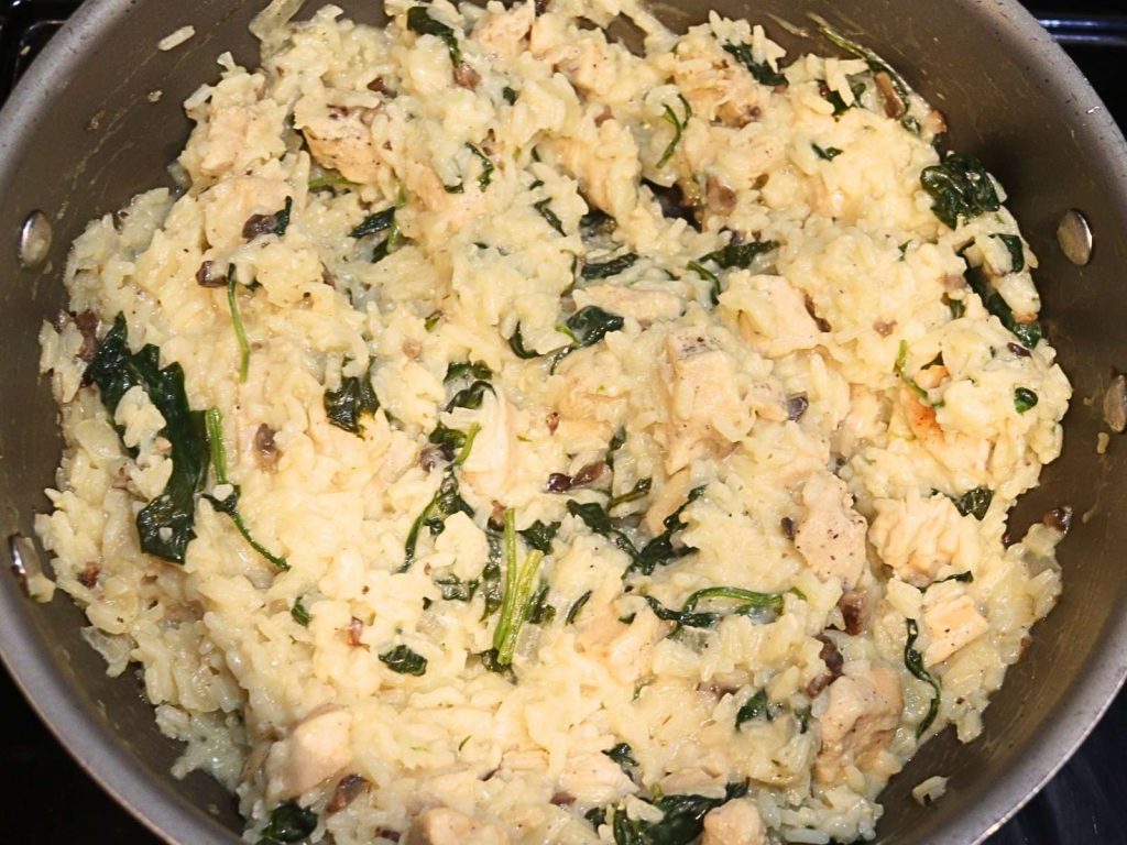 white rice with chunks of chicken breast and spinach cooked in it 