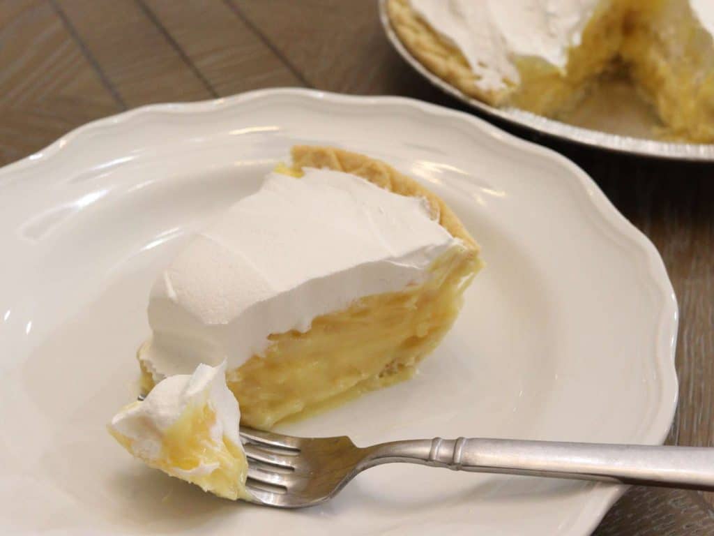 slice of creamy pineapple pie with cool whip on a white plate