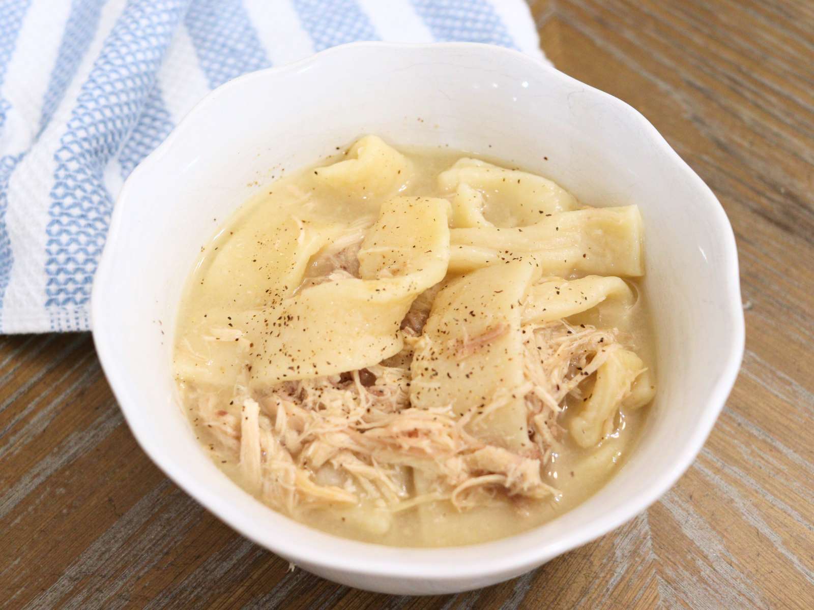 homemade chicken and dumplings in a white bowl