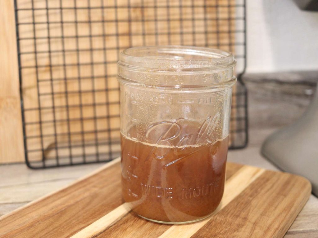 orange/brown syrup in mason jar sitting on wooden cutting board