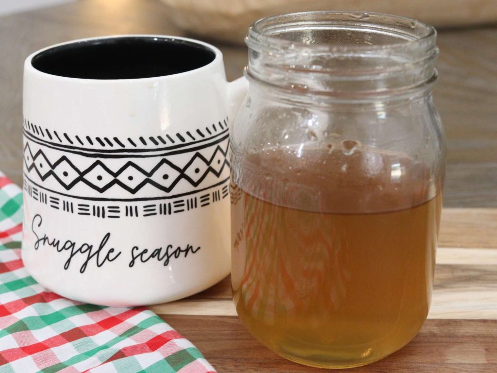 homemade peppermint syrup in a mason jar sitting next to a coffee mug