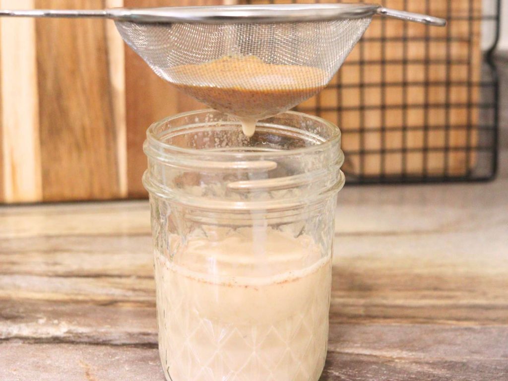 homemade pumpkin spice coffee creamer being strained over a glass mason jar