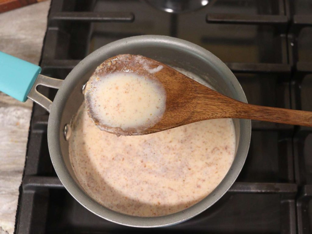 ingredients for homemade pumpkin pie creamer in a small pot with wooden spoon