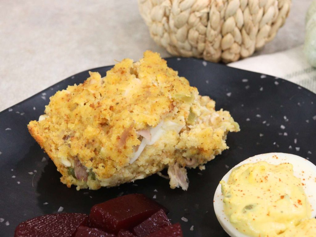 cornbread dressing sitting next to deviled eggs and cranberry sauce on black plate