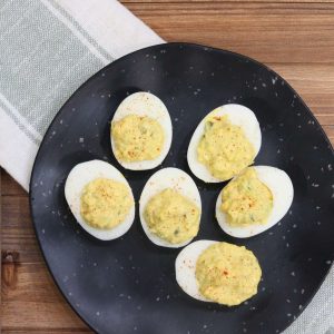 holiday deviled eggs sitting on a black plate