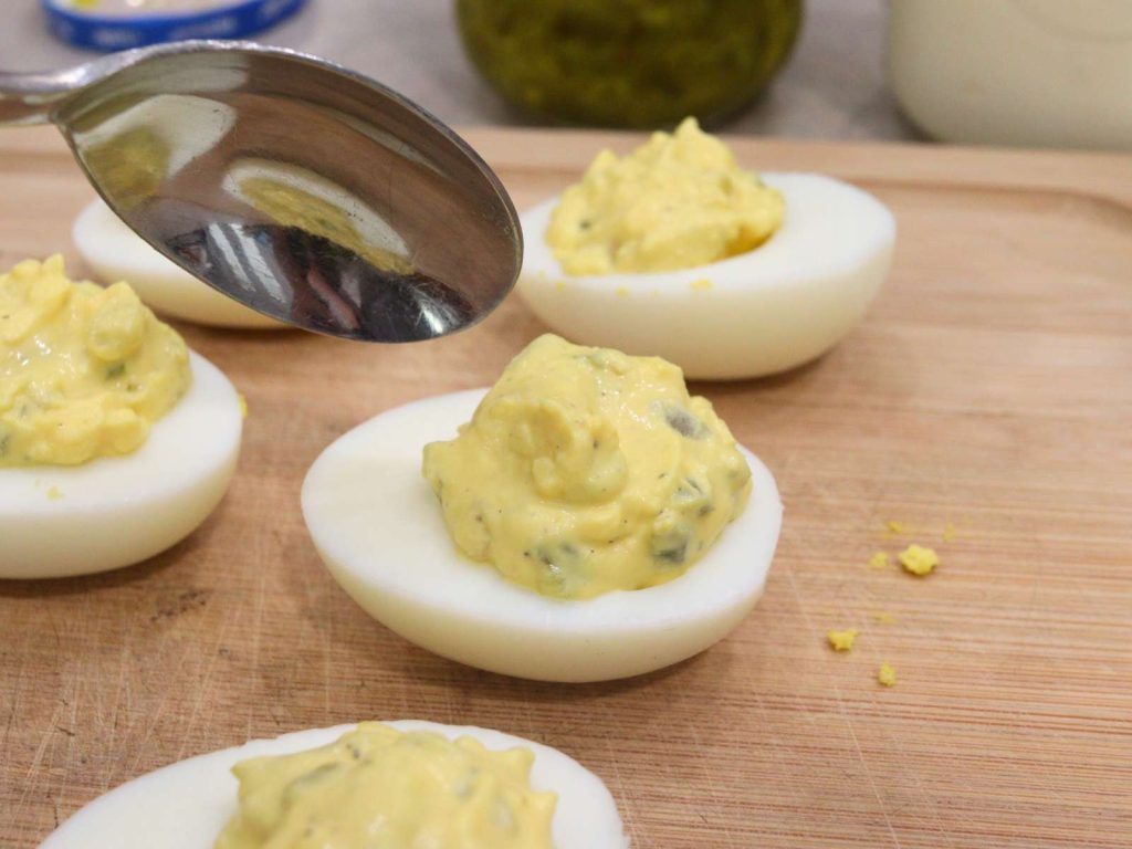 deviled egg being filled with a silver spoon
