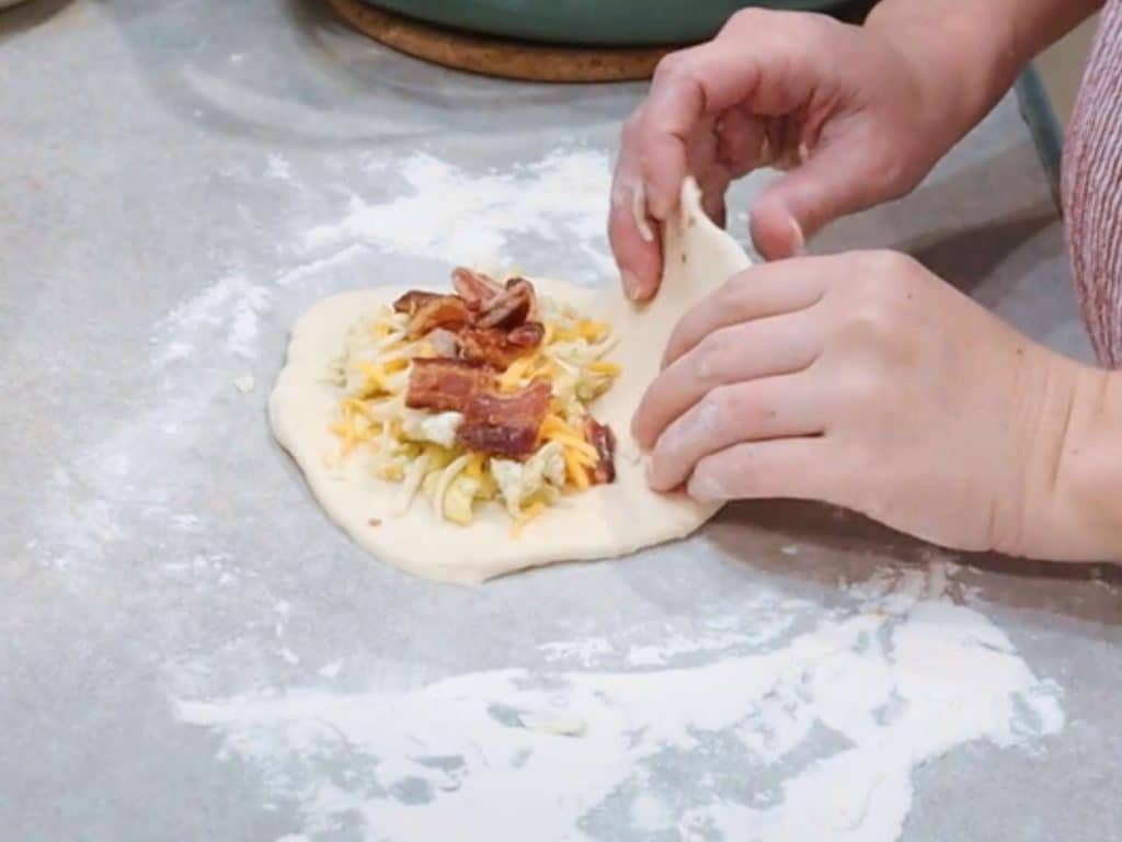 breakfast hot pocket dough with bacon, egg, and cheese on kitchen counter