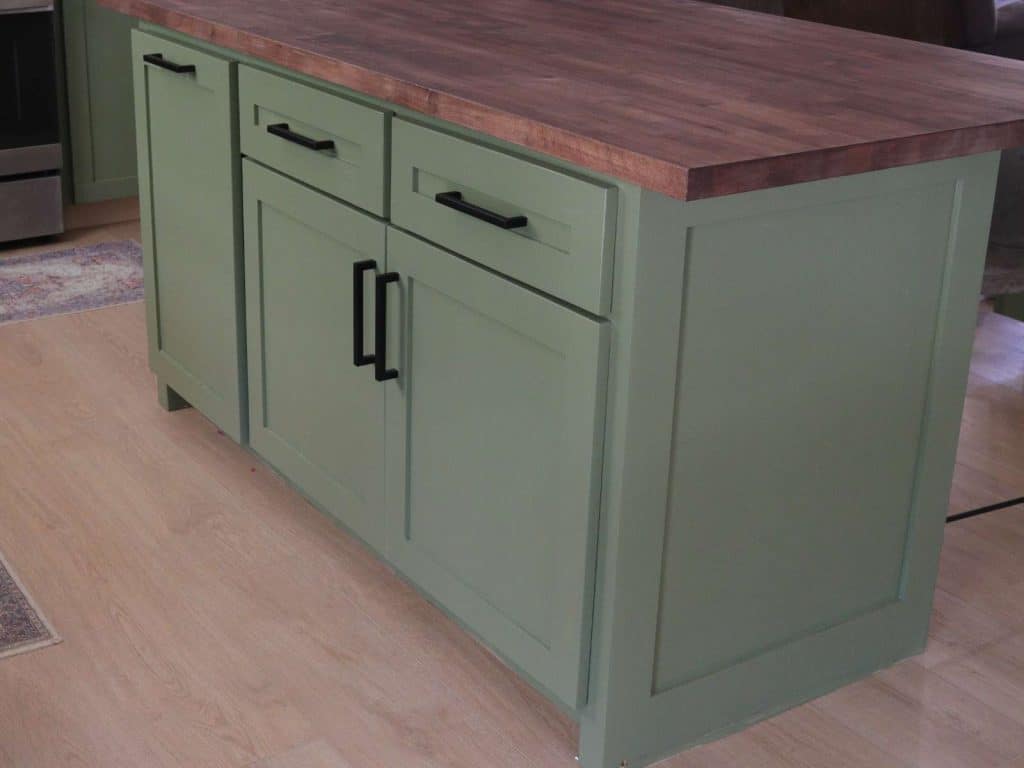 small green kitchen island with butcher block countertop