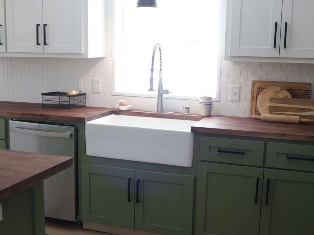 large white farmhouse sink in green kitchen