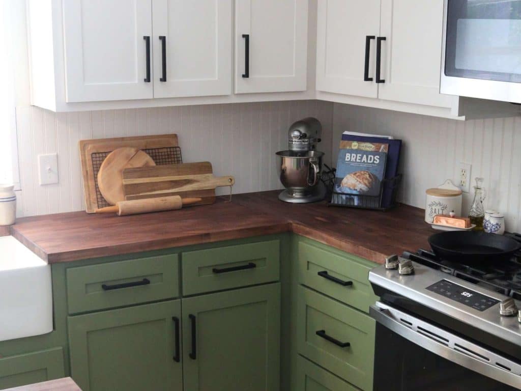 green and white kitchen cabinets with butcher block countertop