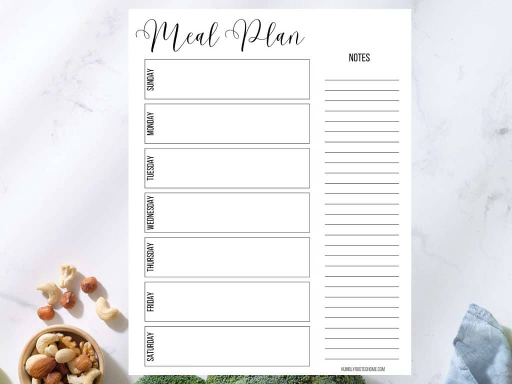 one weekly meal planning calendar with list sitting on white kitchen counter