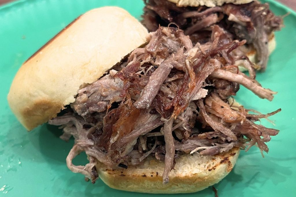 homemade slider buns with pulled pork on a green plate