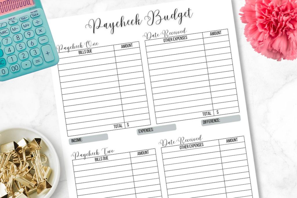 budget printable on white desk with pink flower, calculator, and paper clips