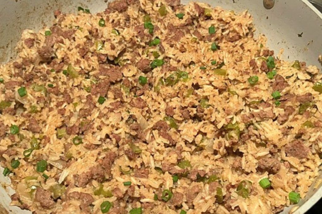 rice and ground meat dish in pot with green onions on top