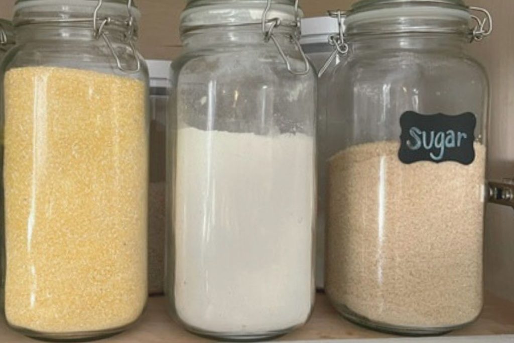 LARGE GLASS CONTAINERS FULL OF DRY BAKING GOODS