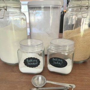 Glass canisters with dry baking goods sitting on wooden counter