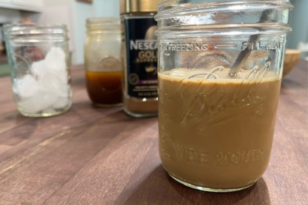 glass mason jar with latte mixture with ingredients in background