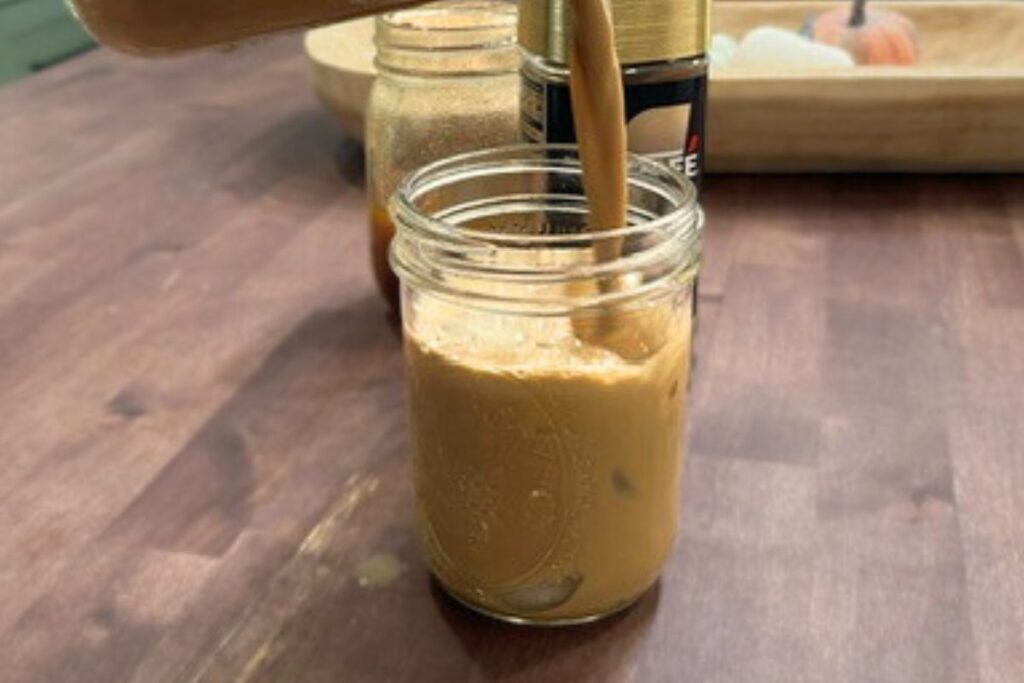 iced latte being poured into mason jar