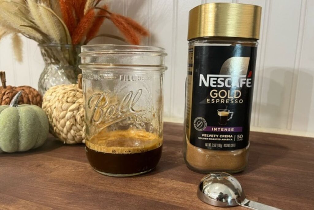 instant espresso next to glass jar with espresso in it on wooden counter