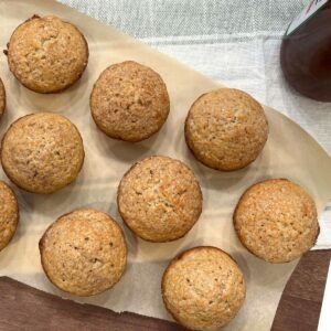 muffins on parchment paper sitting next to jar of apple butter