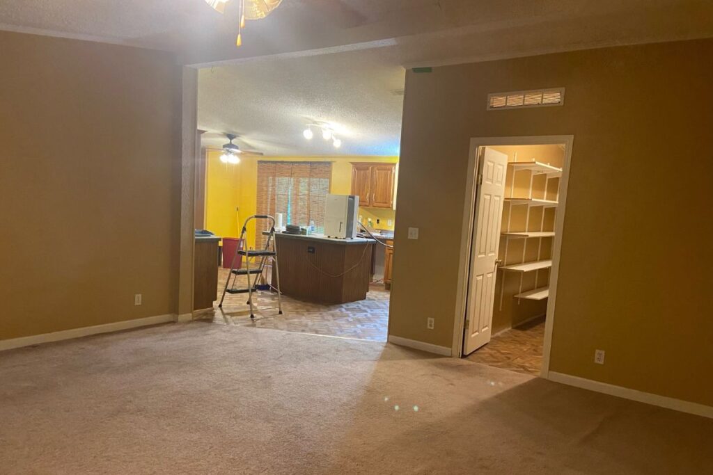 dated double wide mobile home living room with old carpet and dark colored walls