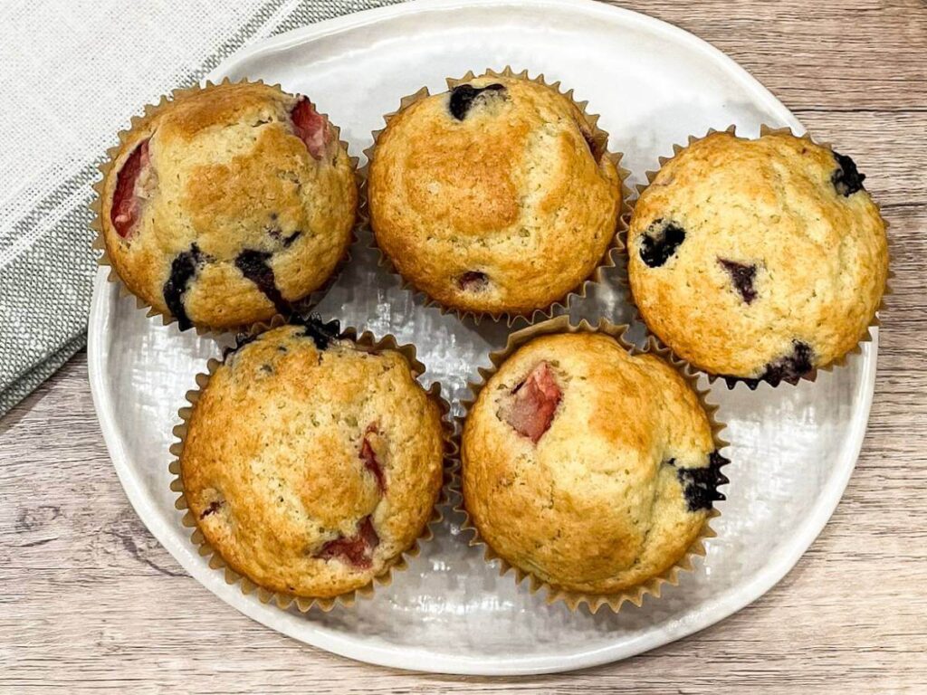 white plate with mixed berry muffins sitting on it
