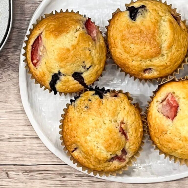 muffins with blueberries and strawberries sitting on a white platter