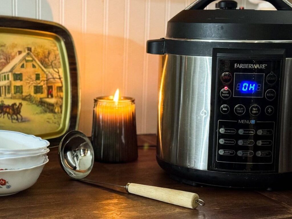 electric pressure cooker sitting on wooden counter next to ladle and bowls